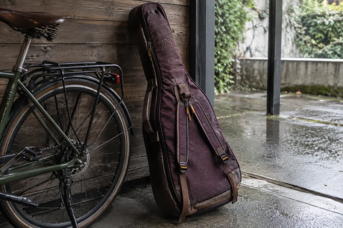 Housse rembourrée près d’un vélo sous un abri, avec des gouttes de pluie visibles sur le tissu.
