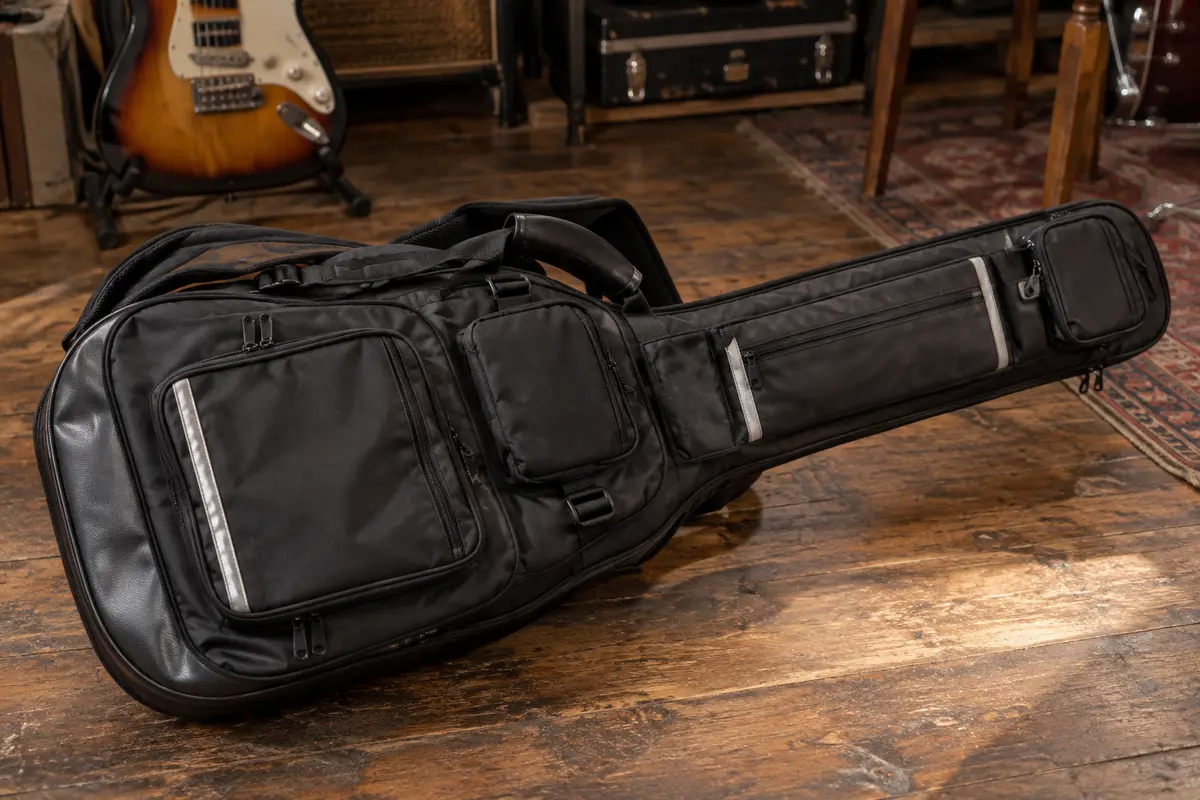 Housse noire rembourrée pour guitare électrique, avec poches, bandes réfléchissantes et bretelles.