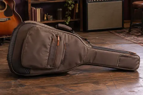 Housse de guitare brune rembourrée avec ses poches extérieures, posée sur un sol de bois patiné